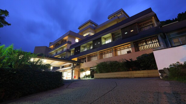 A multi-story hotel with a modern architectural design, featuring balconies and a well-lit entrance. - Hotel Futaba (Yuzawa)