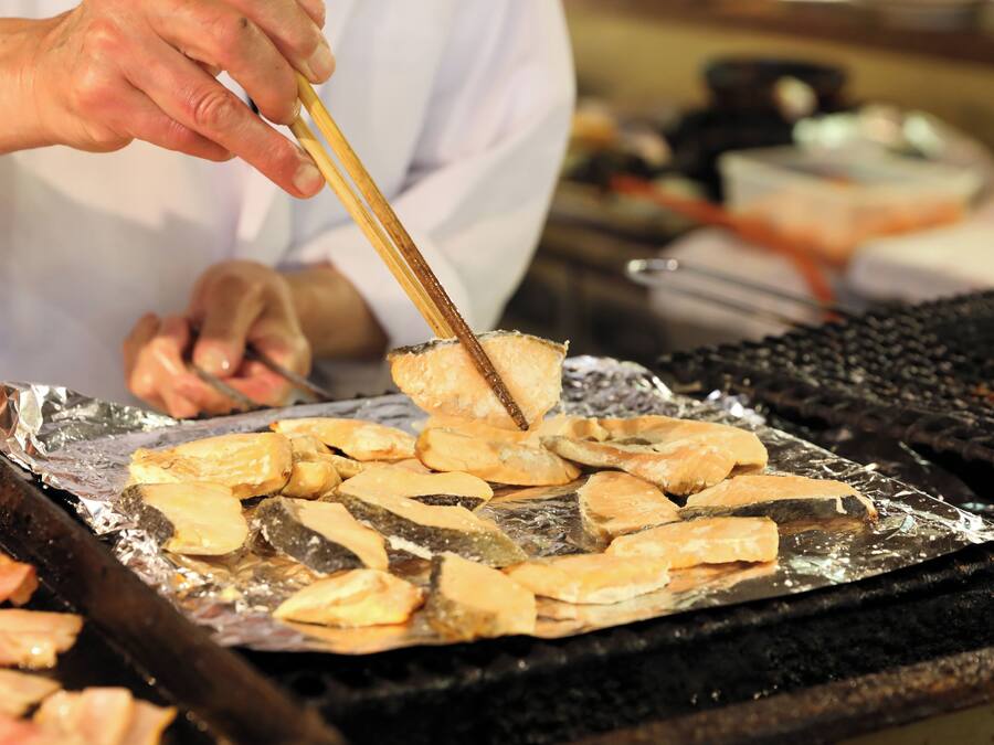 A person grilling fish on a grill.