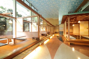 Un interior moderno con bancos y mesas de madera, ventanas amplias y un techo con diseño de nubes.