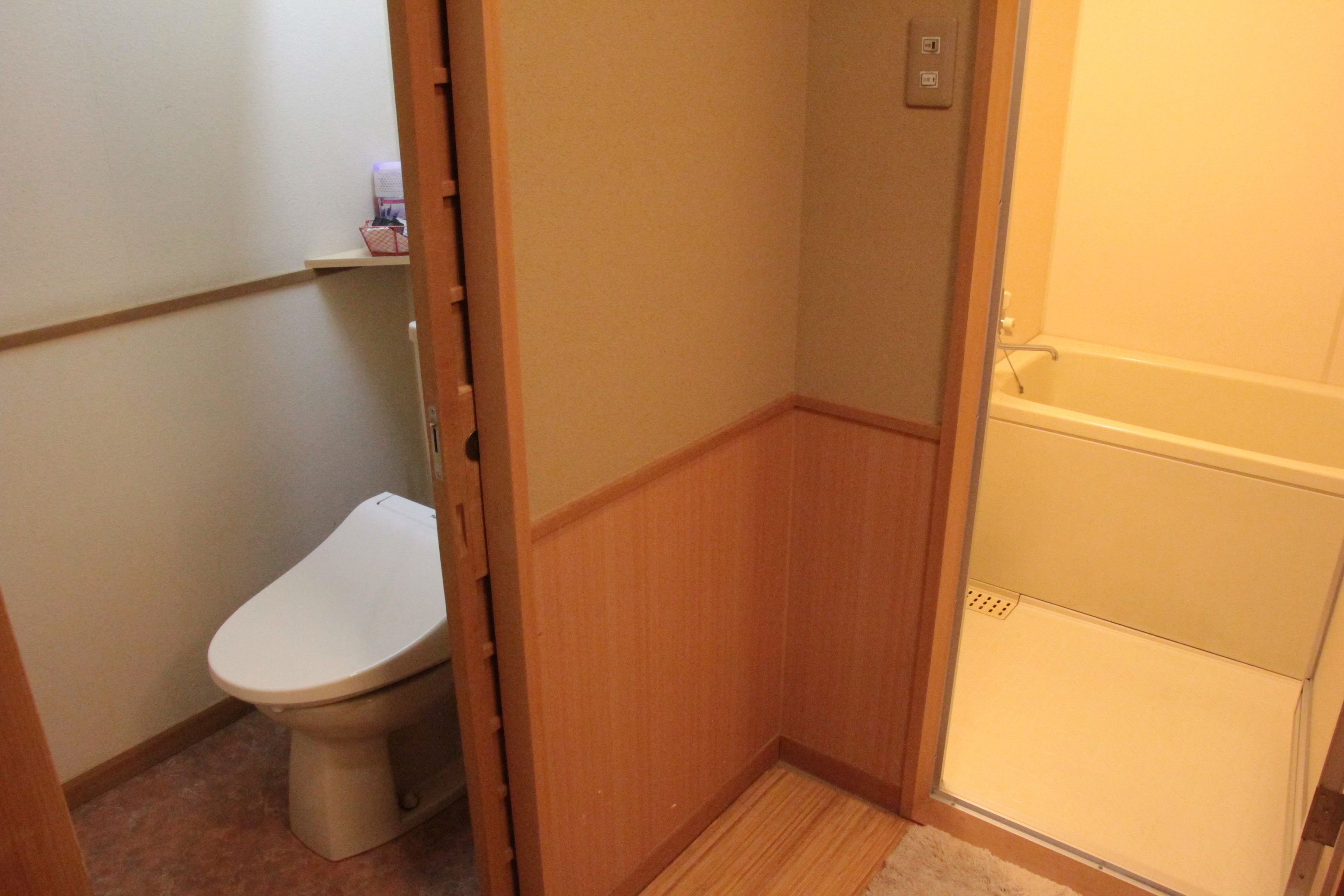 A small bathroom with a toilet, a shower stall, and a wooden floor.