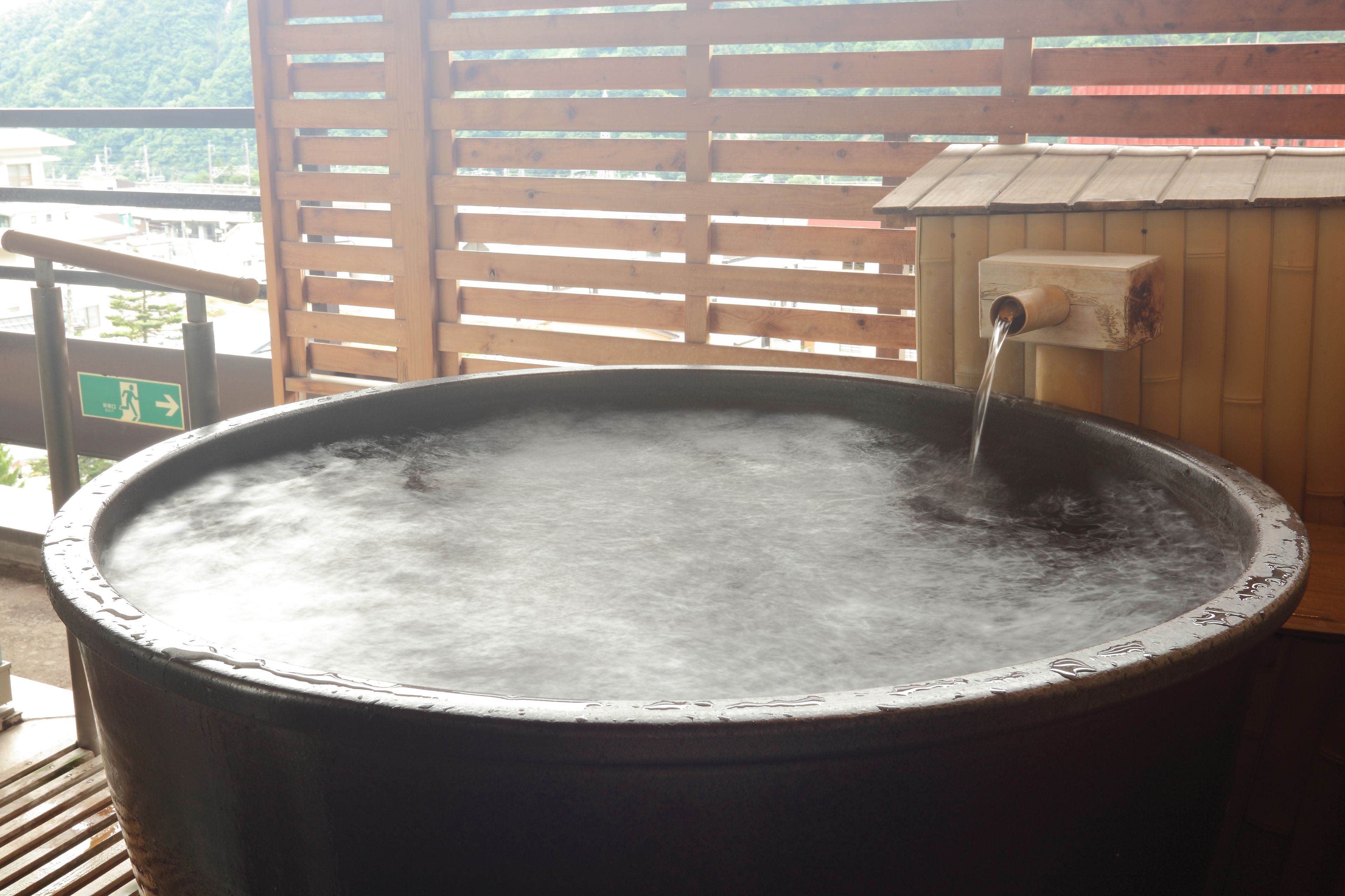 A large outdoor hot tub with a wooden structure and a water spout.