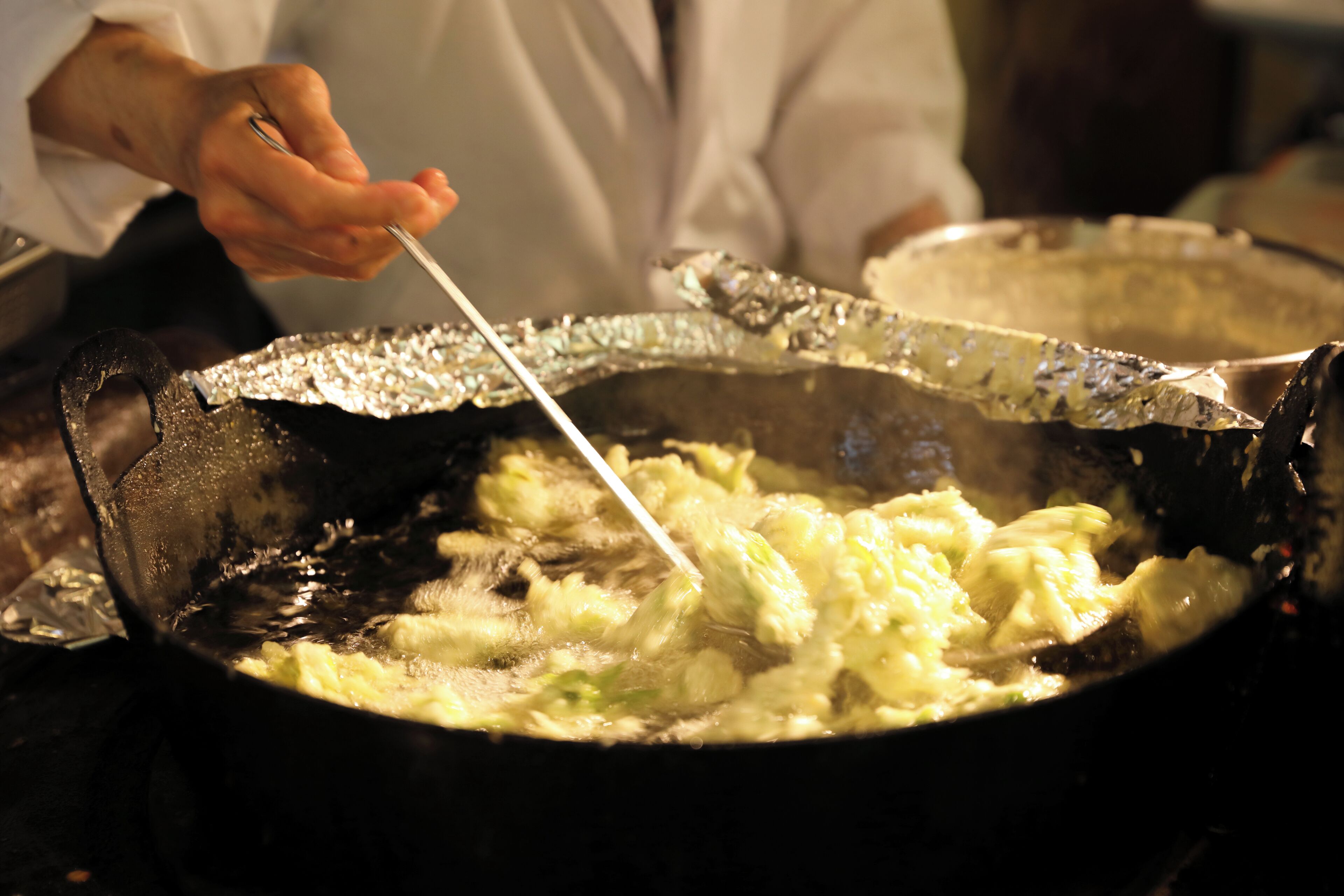 A person cooking in a pan with a spatula.