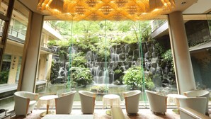 A modern lobby with a waterfall view, seating area, and a decorative ceiling light.