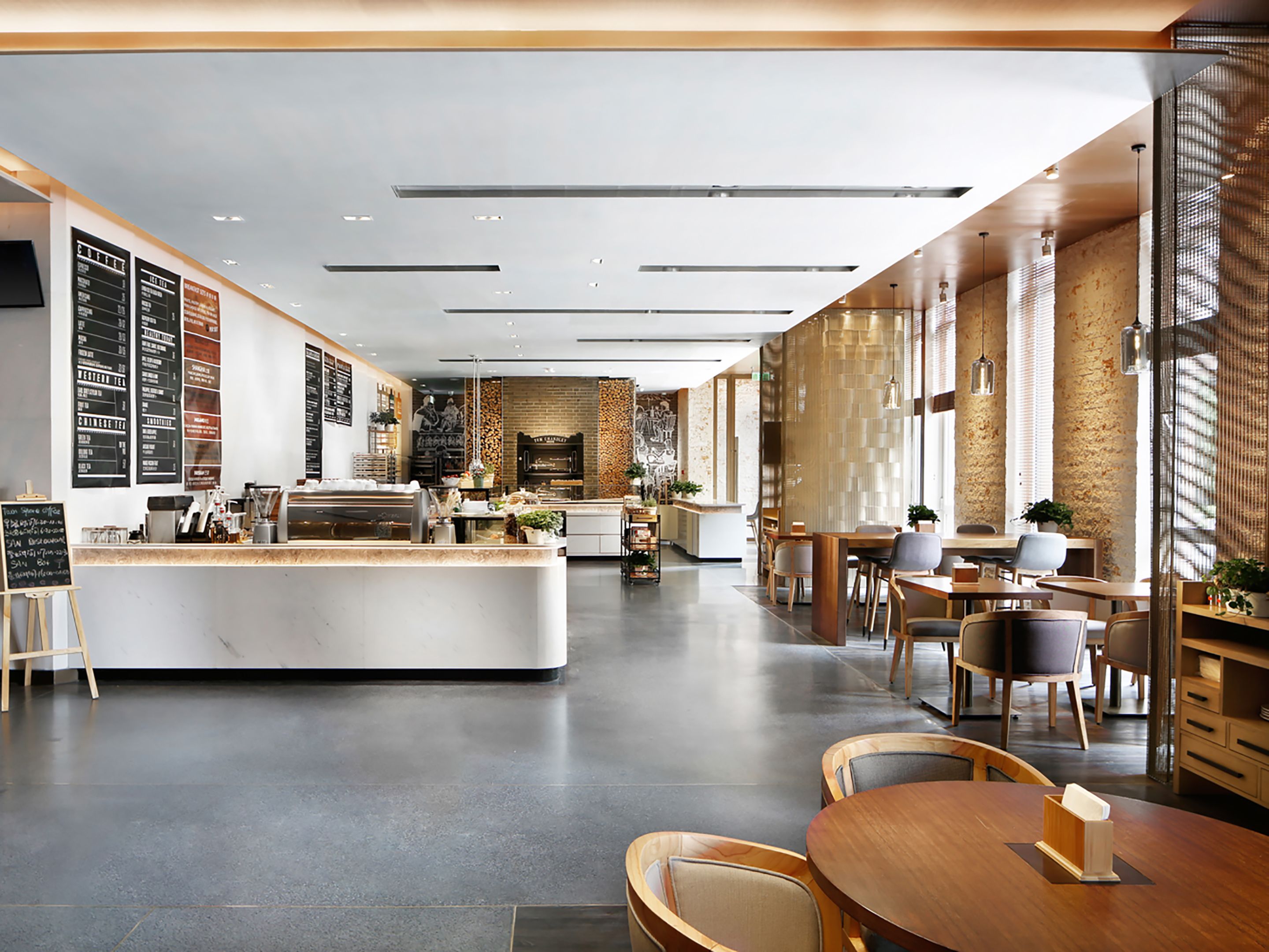 A modern cafe with a central counter, seating area, and a brick wall. - Artyzen Habitat Dongzhimen Beijing (Beijing)