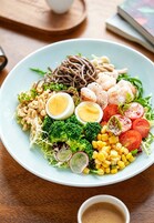 A plate of food with various items including noodles, shrimp, eggs, vegetables, and corn.