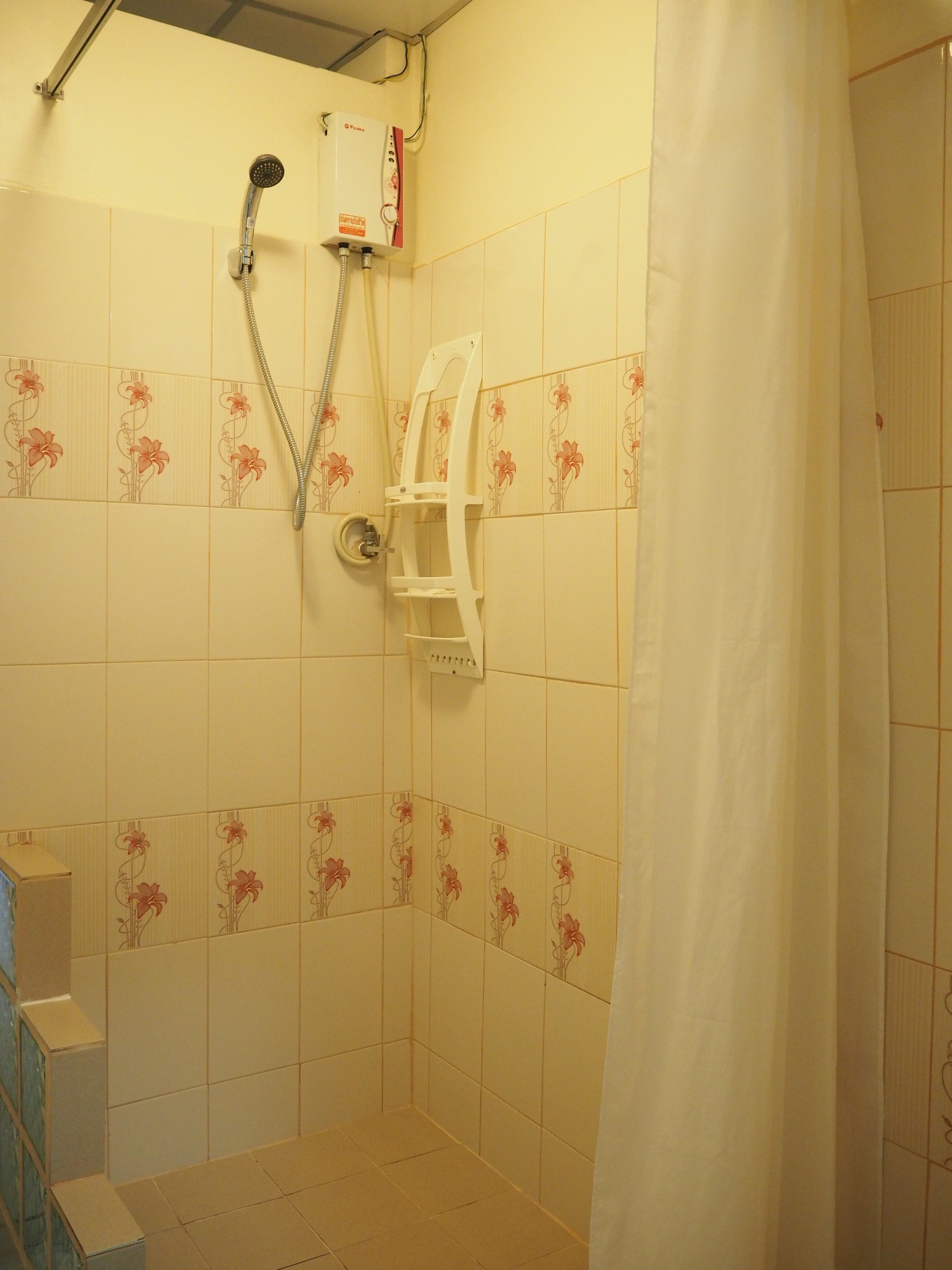 A shower with a handheld showerhead and a wall-mounted faucet.