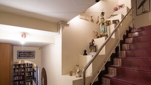 A staircase with a handrail, a bookshelf, and various decorative items on the walls. - Stefans Guesthouse (Pattaya)
