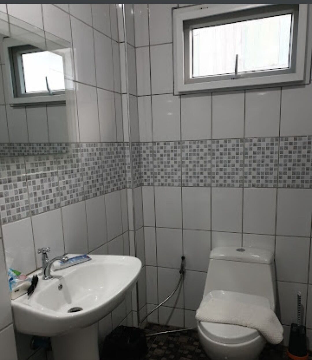 Ein Badezimmer mit einem weißen Waschbecken, einer Toilette und einem Fenster über der Toilette.