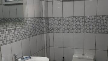 Ein Badezimmer mit einem weißen Waschbecken, einer Toilette und einem Fenster über der Toilette.