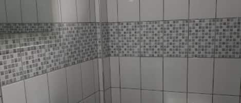 Un baño con lavamanos y retrete blancos, y una ventana sobre el inodoro.