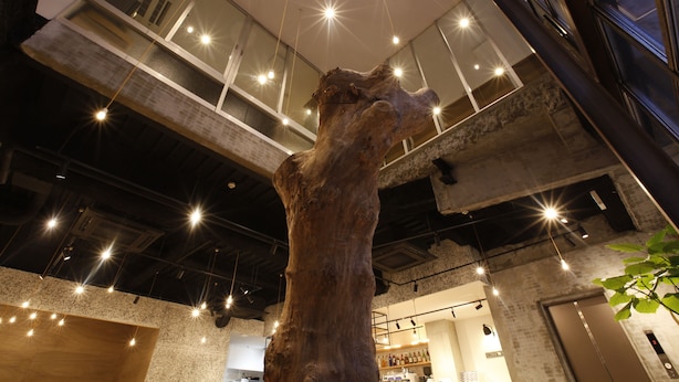 Een modern interieur met openliggende bakstenen muren, een houten sculptuur en een tussenverdieping met glazen balustrades.