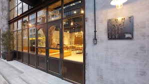 Een modern hotel met grote ramen, een zichtbaar restaurant binnenin en een bord met de tekst 'KNUT HOTEL'.