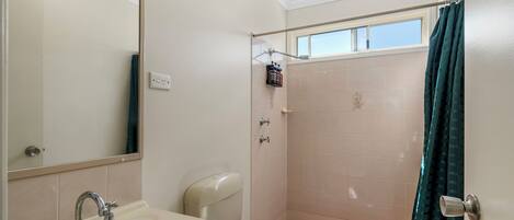 Une salle de bain comprenant un lavabo, des toilettes et un espace douche.