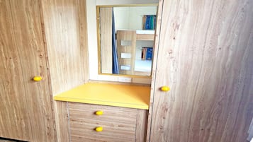A wooden wardrobe with a mirror, a yellow countertop, and four drawers.