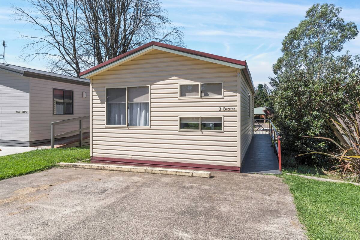 A small, single-story mobile home with a red roof and beige siding, labeled "3 Executive."