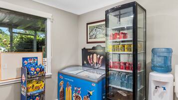 A room with a refrigerator stocked with beverages, a water dispenser, and a snack display.