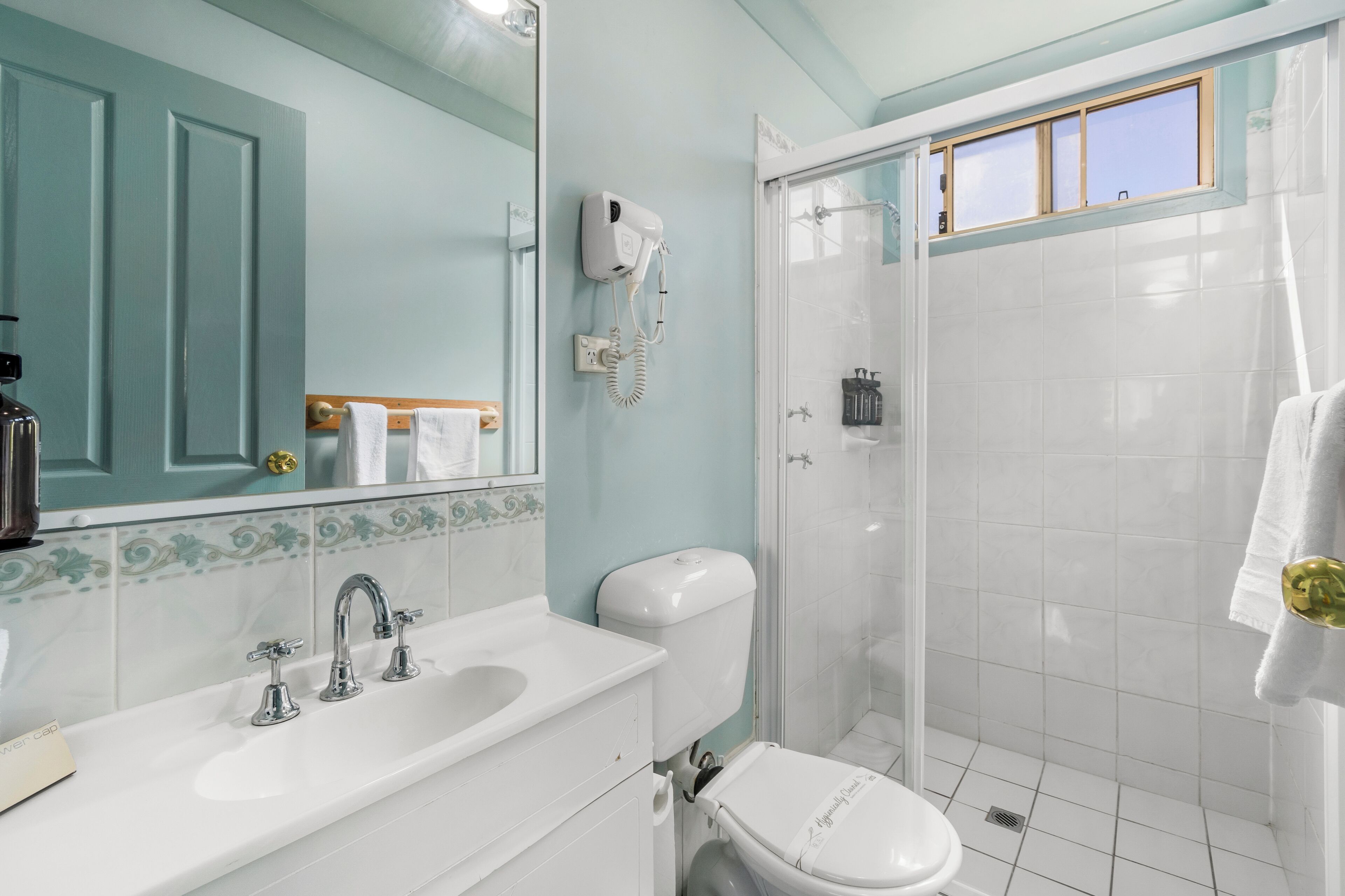 Un baño con lavamanos blanco, inodoro, ducha y espejo.