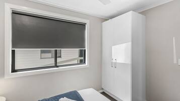 A bedroom with a bed, a window with blinds, a wardrobe, and a ceiling fan.