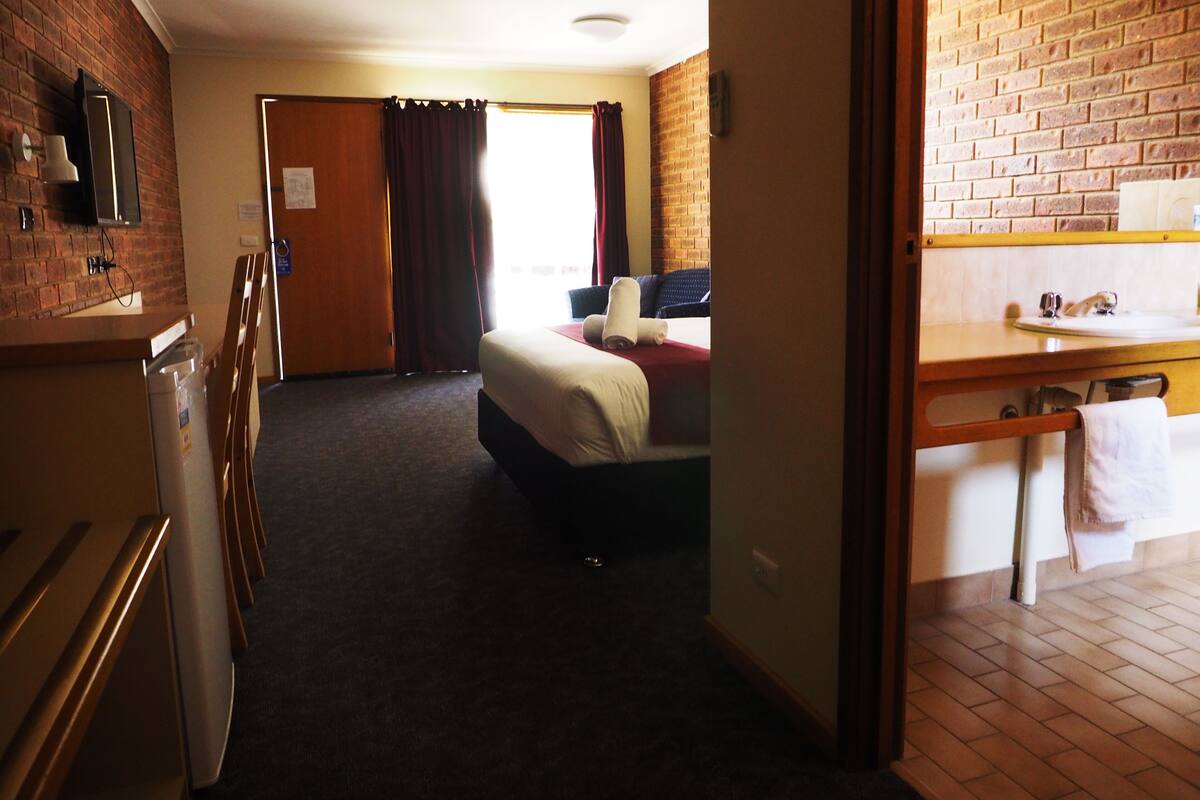 Una habitación de hotel con cama, escritorio, lavabo y espejo.
