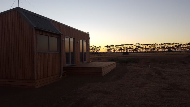 A wooden building with a sloped roof, large windows, and a small porch. - Lara Lodge (Lara)