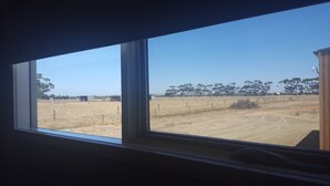 A window with a view of a fenced field and trees. - Lara Lodge (Lara)