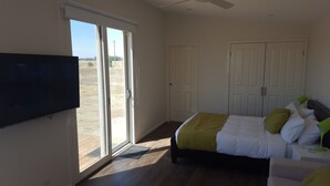 A bedroom with a bed, a TV, a wardrobe, and a sliding glass door leading to an outdoor area. - Lara Lodge (Lara)