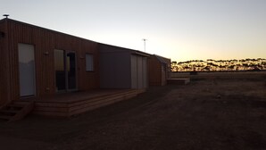 A modern wooden building with a flat roof, large windows, and a small porch. - Lara Lodge (Lara)