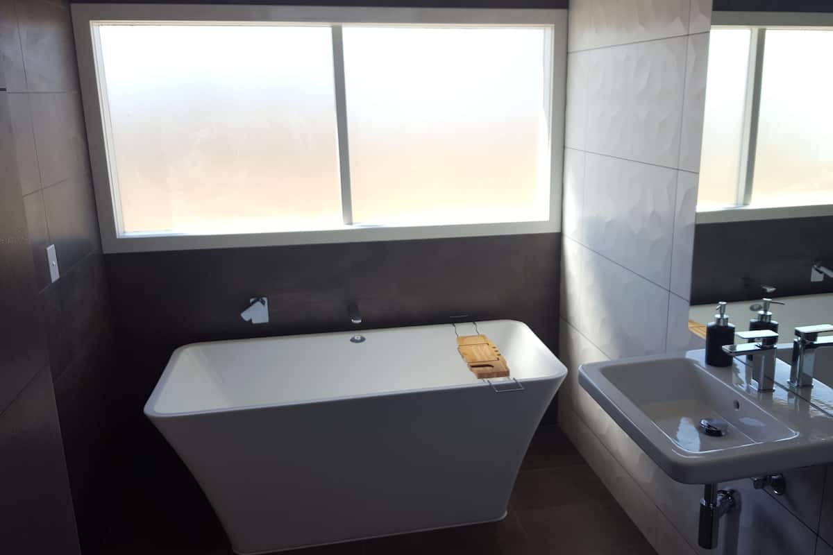 A modern bathroom with a bathtub, a sink, and a large window.