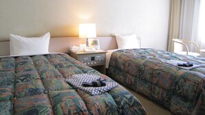 Une chambre d’hôtel avec deux lits, une table de chevet avec une lampe, une horloge et une petite table avec un téléphone et des mouchoirs.