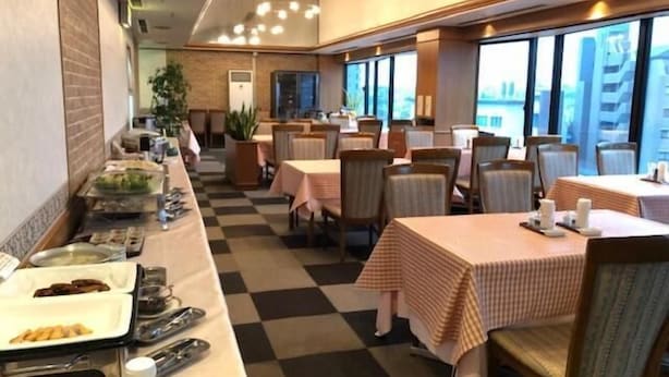 Un restaurant dont le sol est recouvert de carreaux, où les tables sont nappées de tissus à carreaux et où l’on trouve un buffet proposant une variété de plats et d’ustensiles.