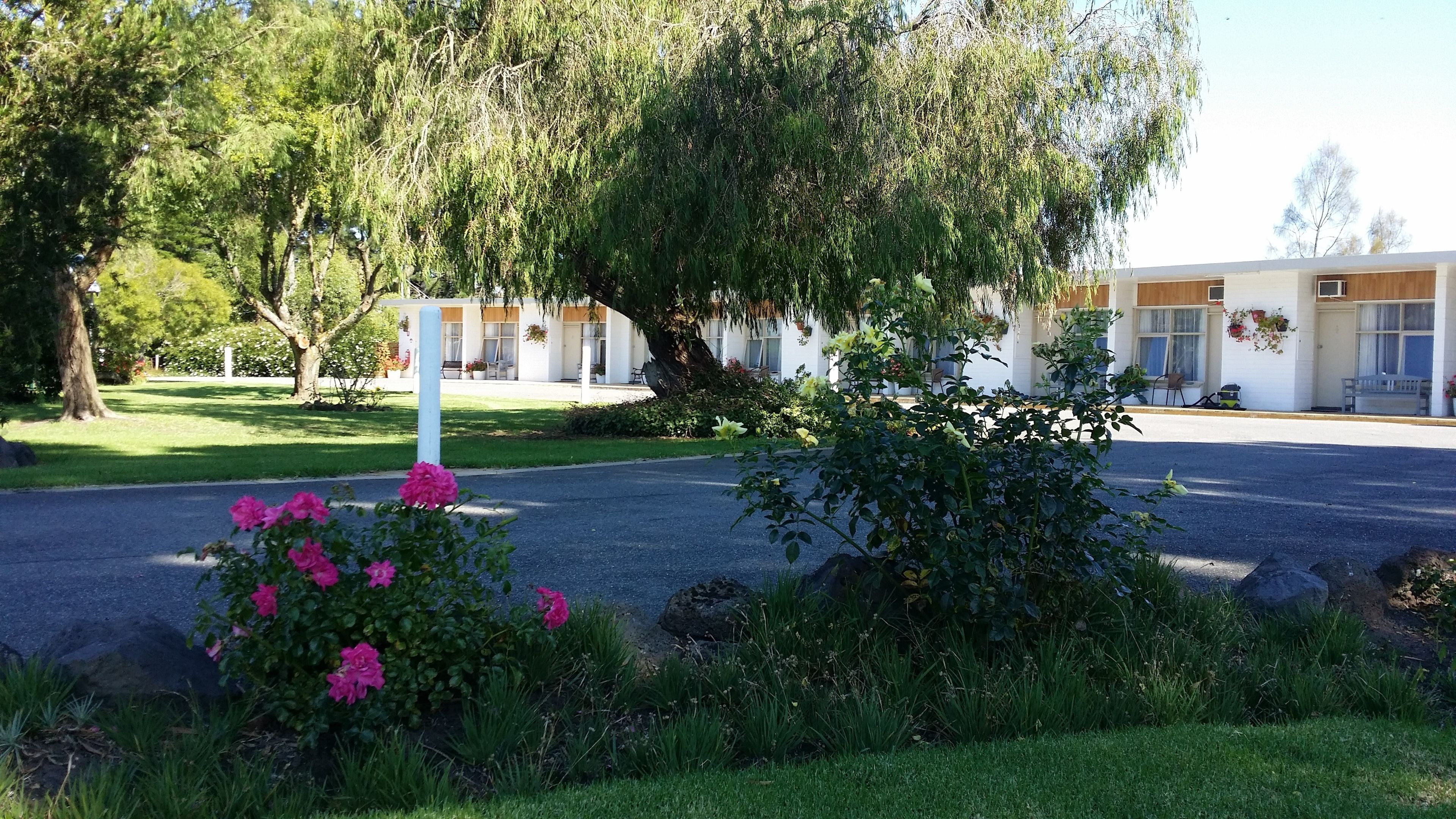 Un hotel con una hilera de edificios blancos, un césped y plantas con flores en primer plano.