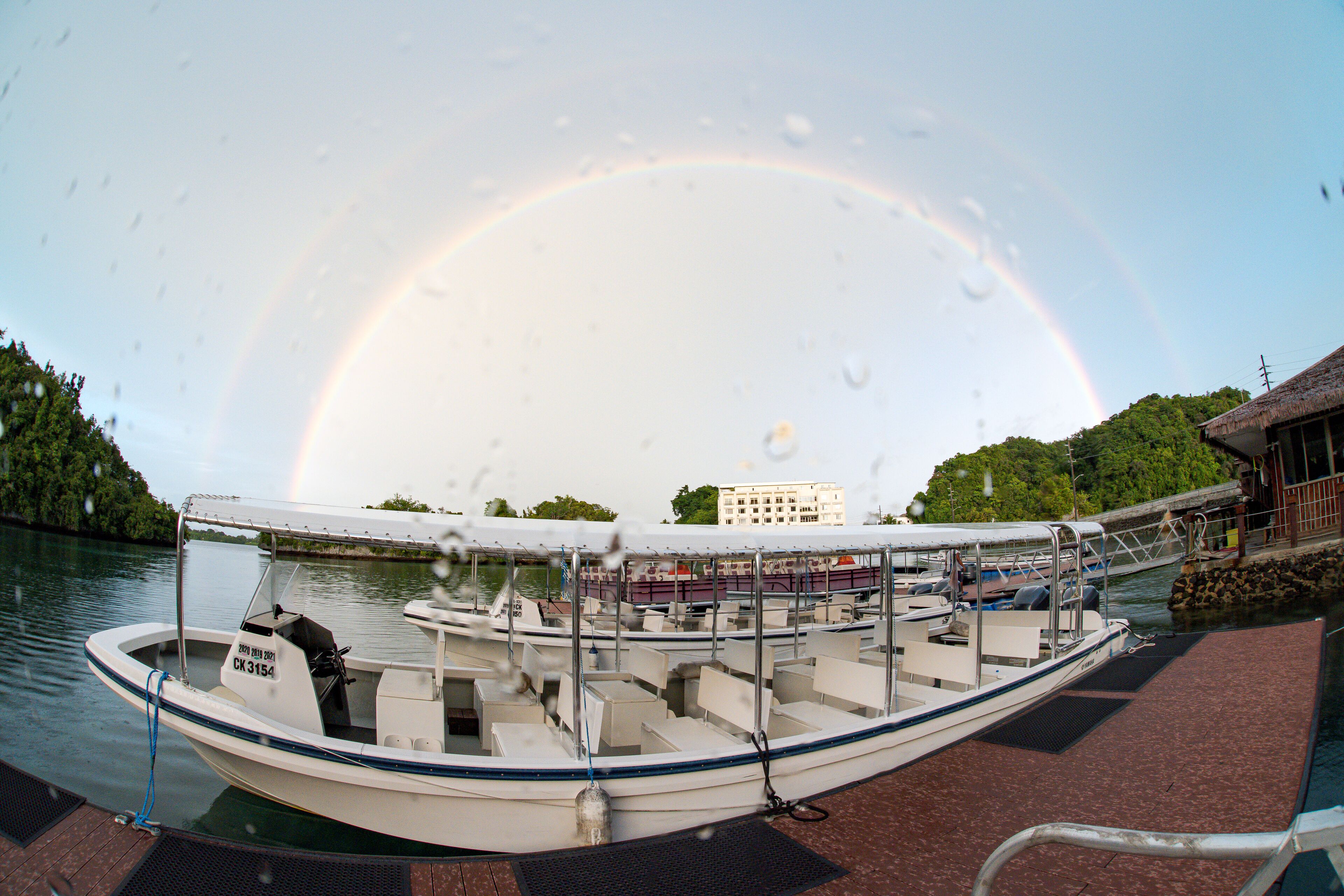 A boat docked at a pier with a rainbow in the background.