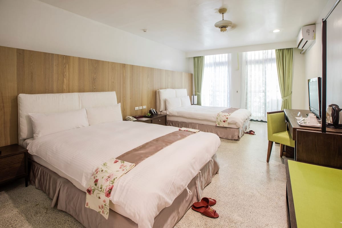 Een hotelkamer met twee bedden, een bureau en een stoel.