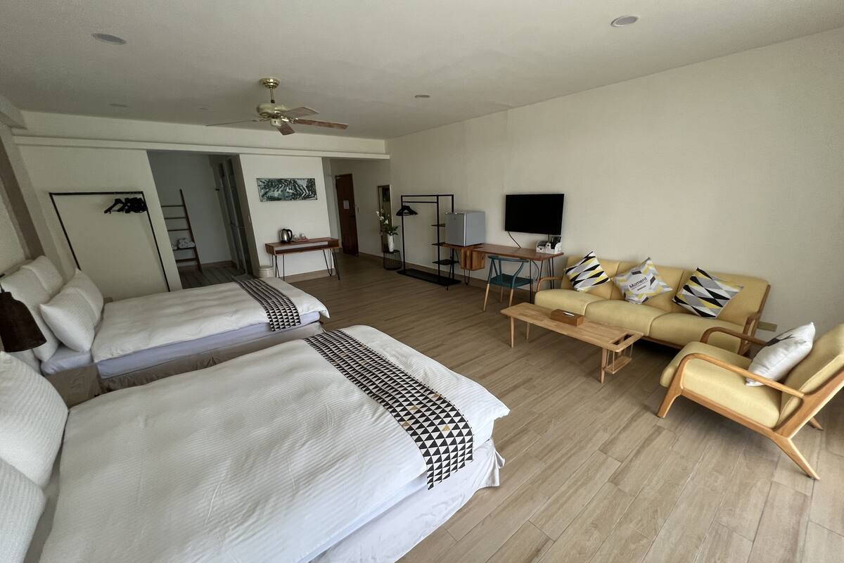 Een hotelkamer met twee bedden, een bank, een televisie en een bureau.
