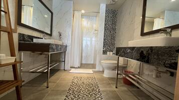 A modern bathroom with two sinks, a toilet, and a shower area.