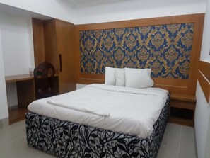 A bedroom with a bed, a desk, and a patterned headboard. - Nagar Valley Hotel (Dhaka)