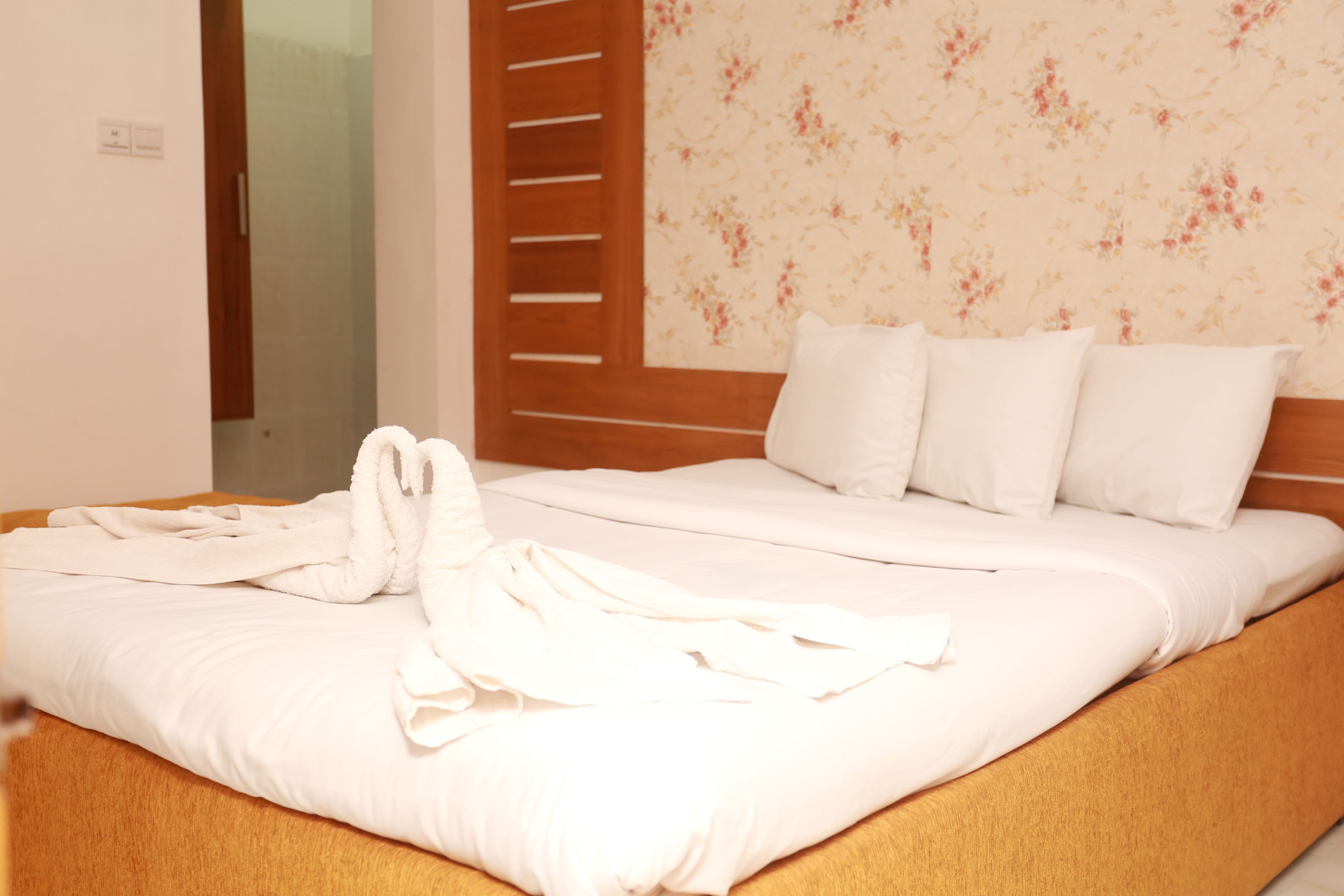Una cama bien hecha con sábanas blancas y un par de toallas blancas dobladas encima.