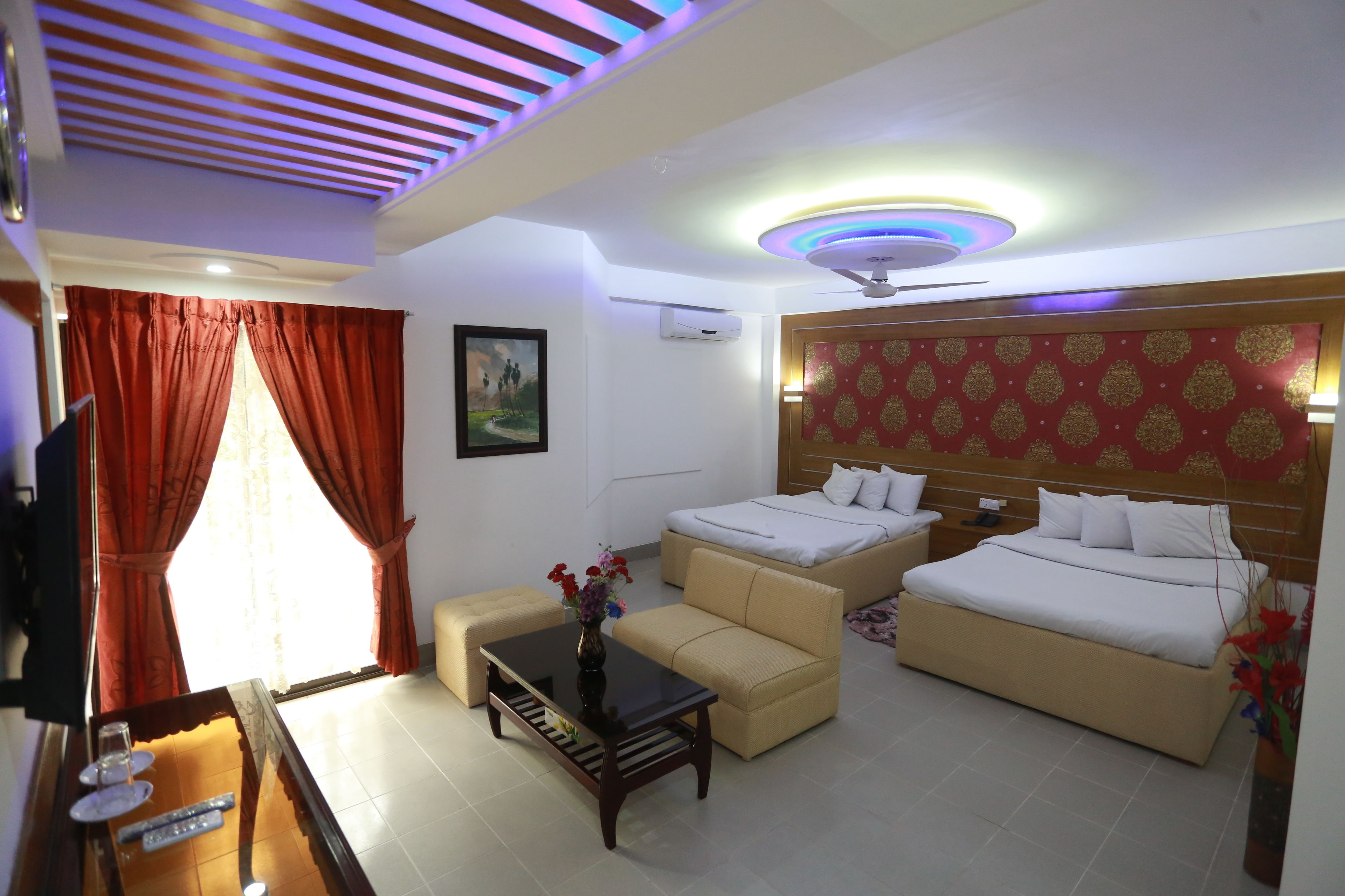 A hotel room with a bed, sofa, and a small table with a vase of flowers.