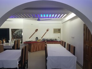 A dining area with two tables, a ceiling fan, and a radio. - Nagar Valley Hotel (Dhaka)