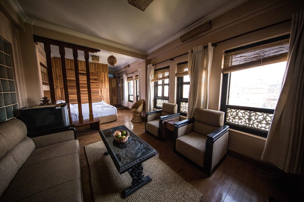A spacious living room with a sofa, armchairs, a coffee table, and a television.