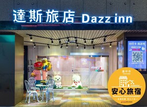 A Dazzinn hotel entrance with a sign in both English and Chinese, a QR code for digital services, and a logo for Taichung Homestay. - Dazz Inn (Taichung)