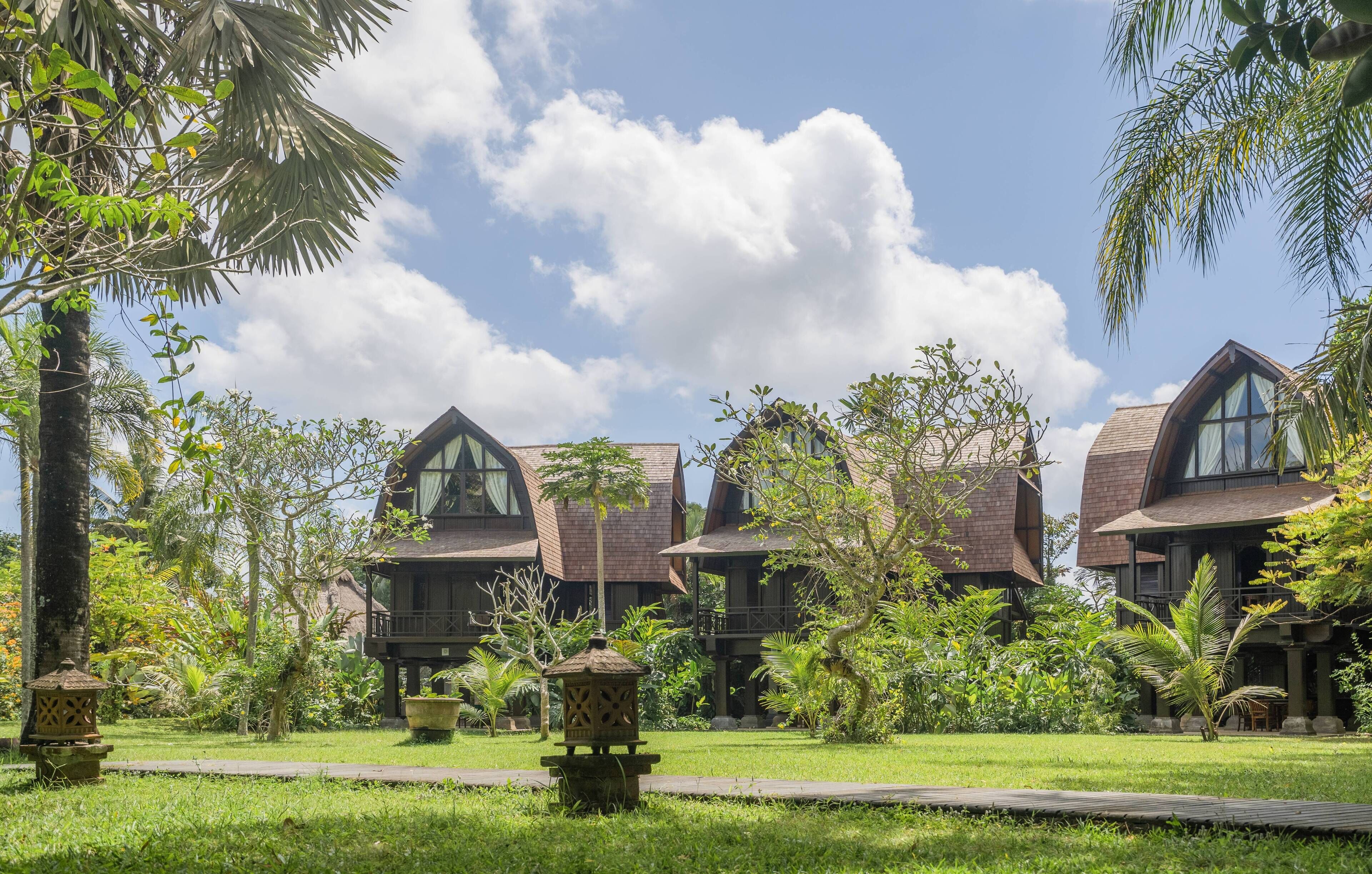 Un resort con diversi edifici in legno, vegetazione rigogliosa e cielo sereno.