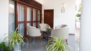 A room with a wooden door, a small table with chairs, and potted plants. - Suriya Arana (Negombo)
