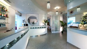 A modern hotel lobby with a reception desk, a seating area, and a bar. - Hotel Felix (Rimini)