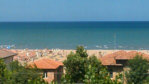 A coastal town with a beach, buildings with red-tiled roofs, and a clear blue sky. - Hotel Felix (Rimini)