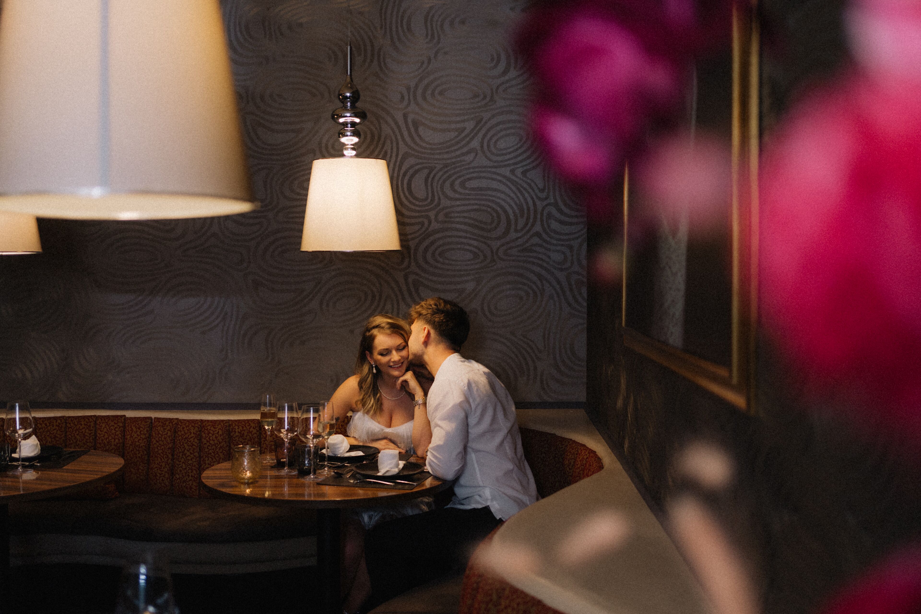 Ein Paar speist in einem Restaurant mit Wandmuster und einer Hängelampe.