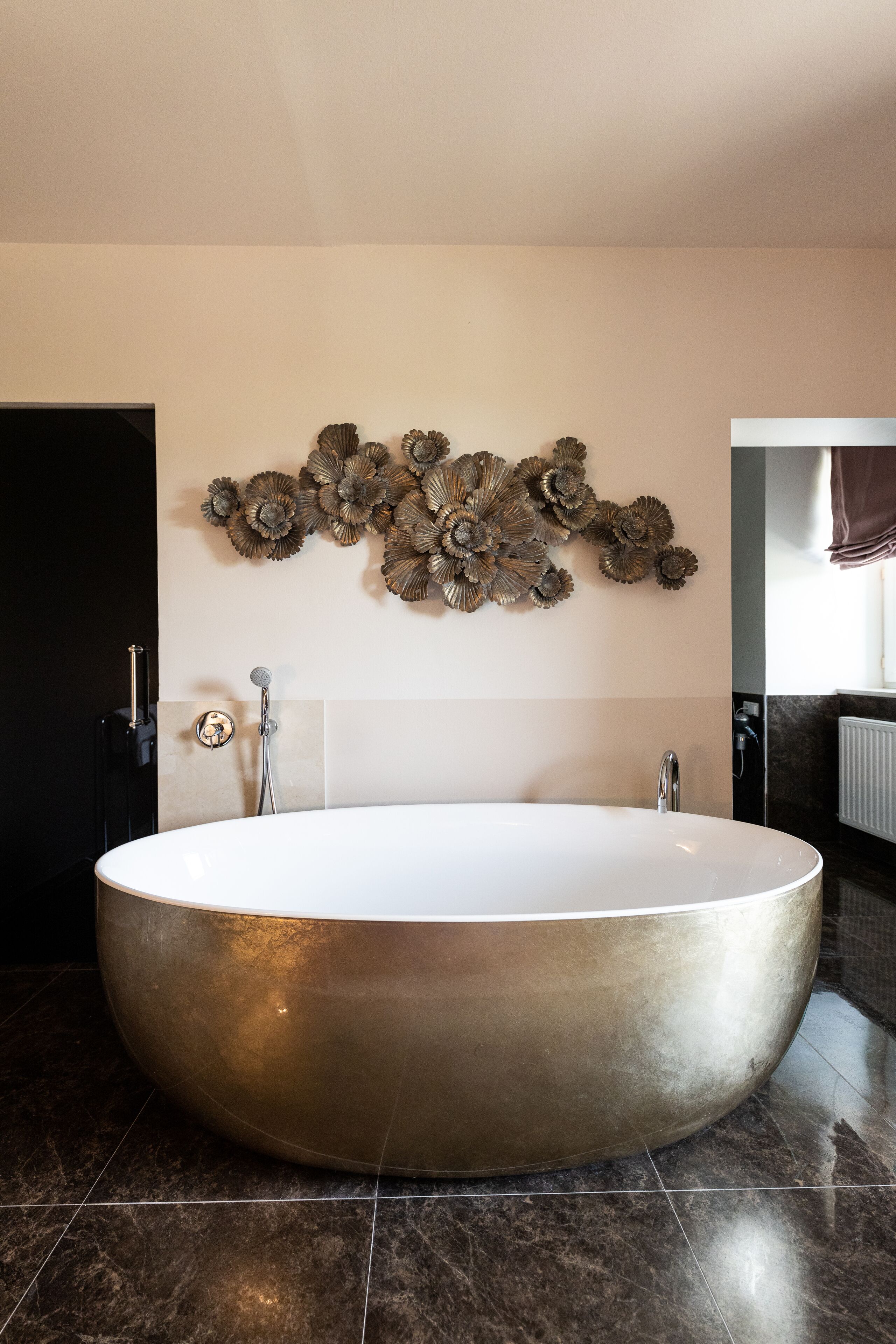 Ein modernes Badezimmer mit einer großzügigen, freistehenden Badewanne, einer Wanddusche und dekorativer Metallwandgestaltung.