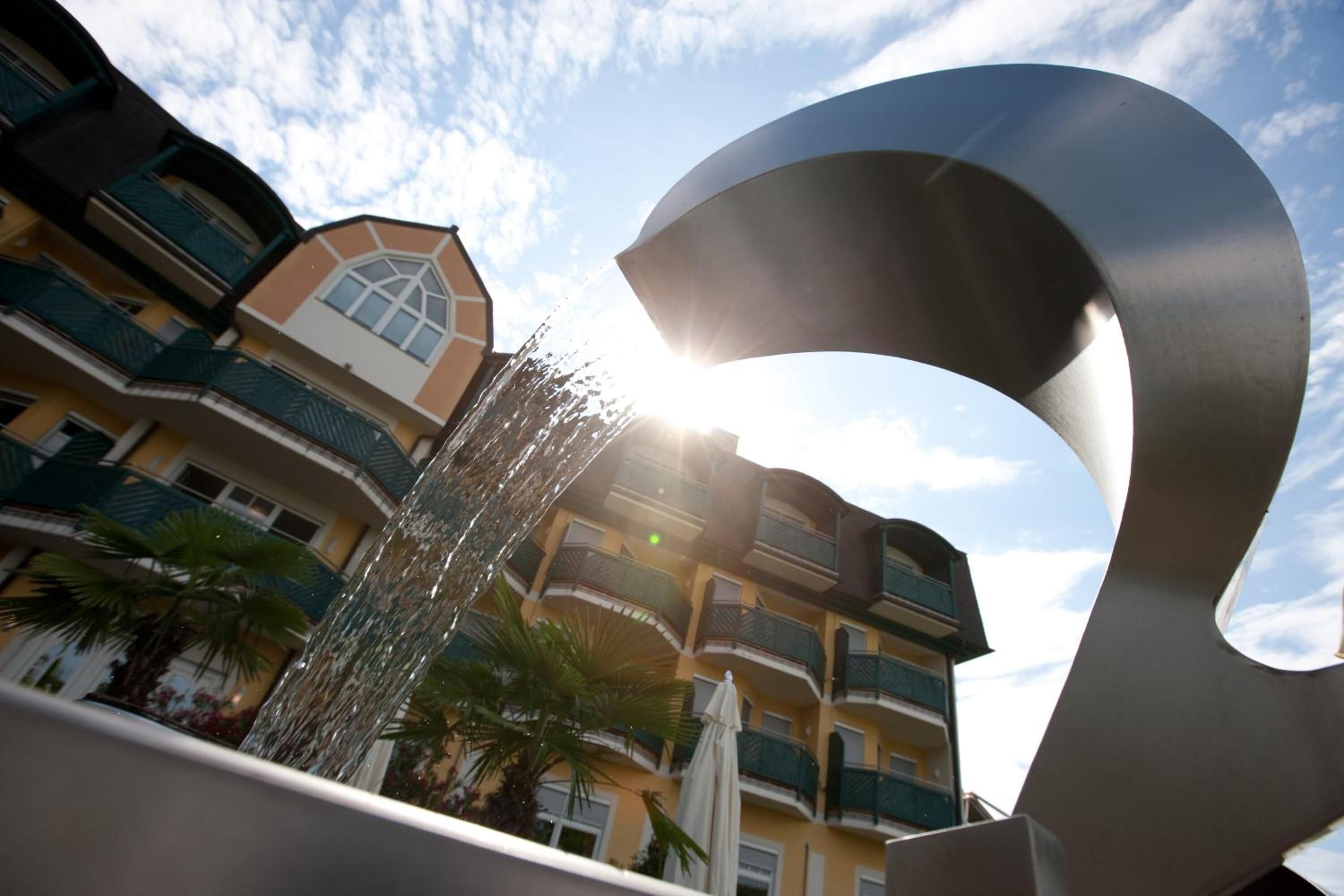 A modern building with balconies and a large metallic sculpture.