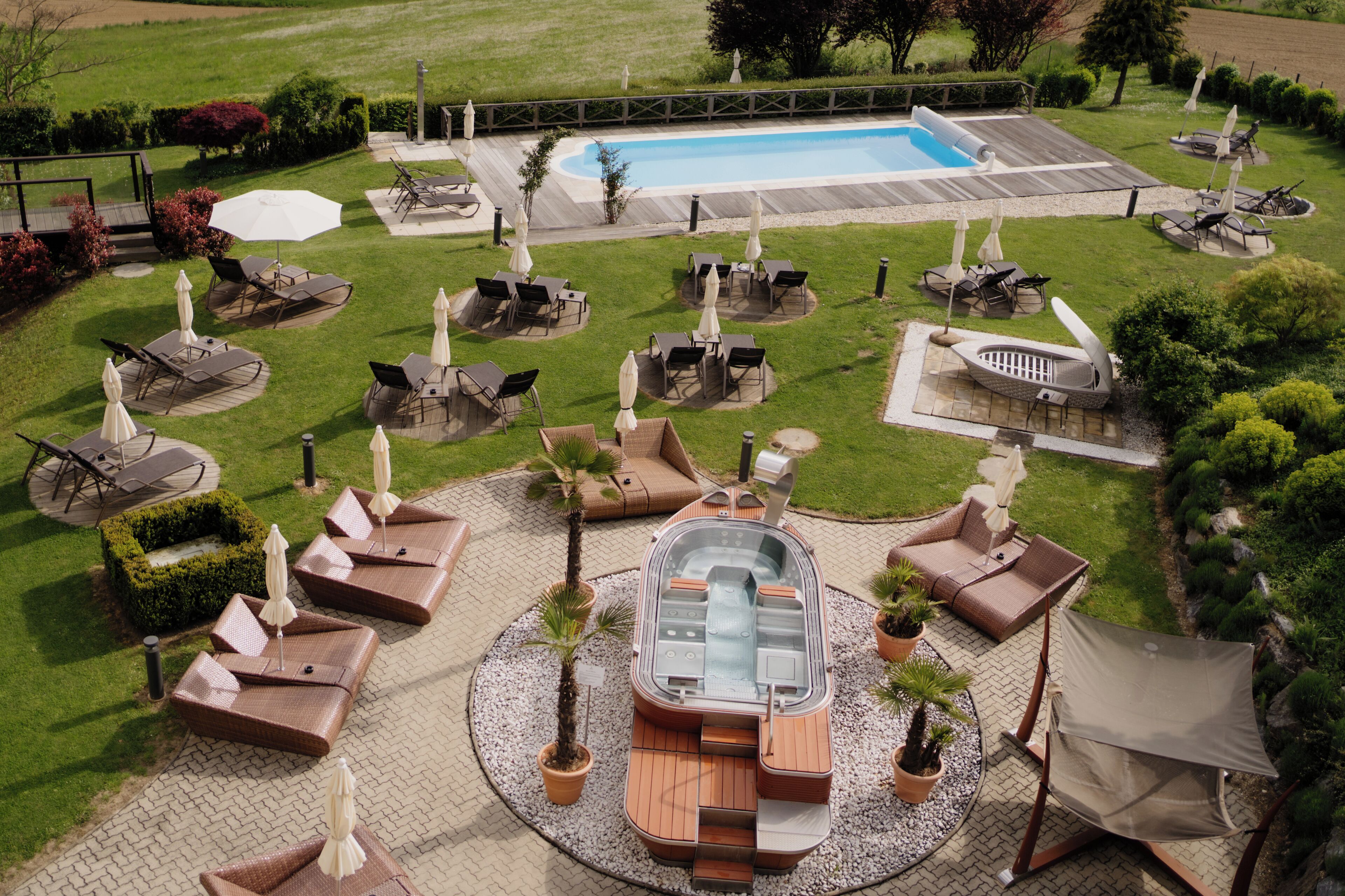 Zona junto a la piscina con sillones de descanso, sombrillas y un jacuzzi.