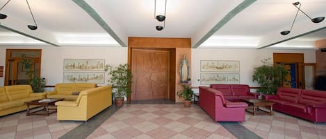 Un vestíbulo amplio con sofás amarillos y rojos, una puerta de madera y obras de arte en las paredes.